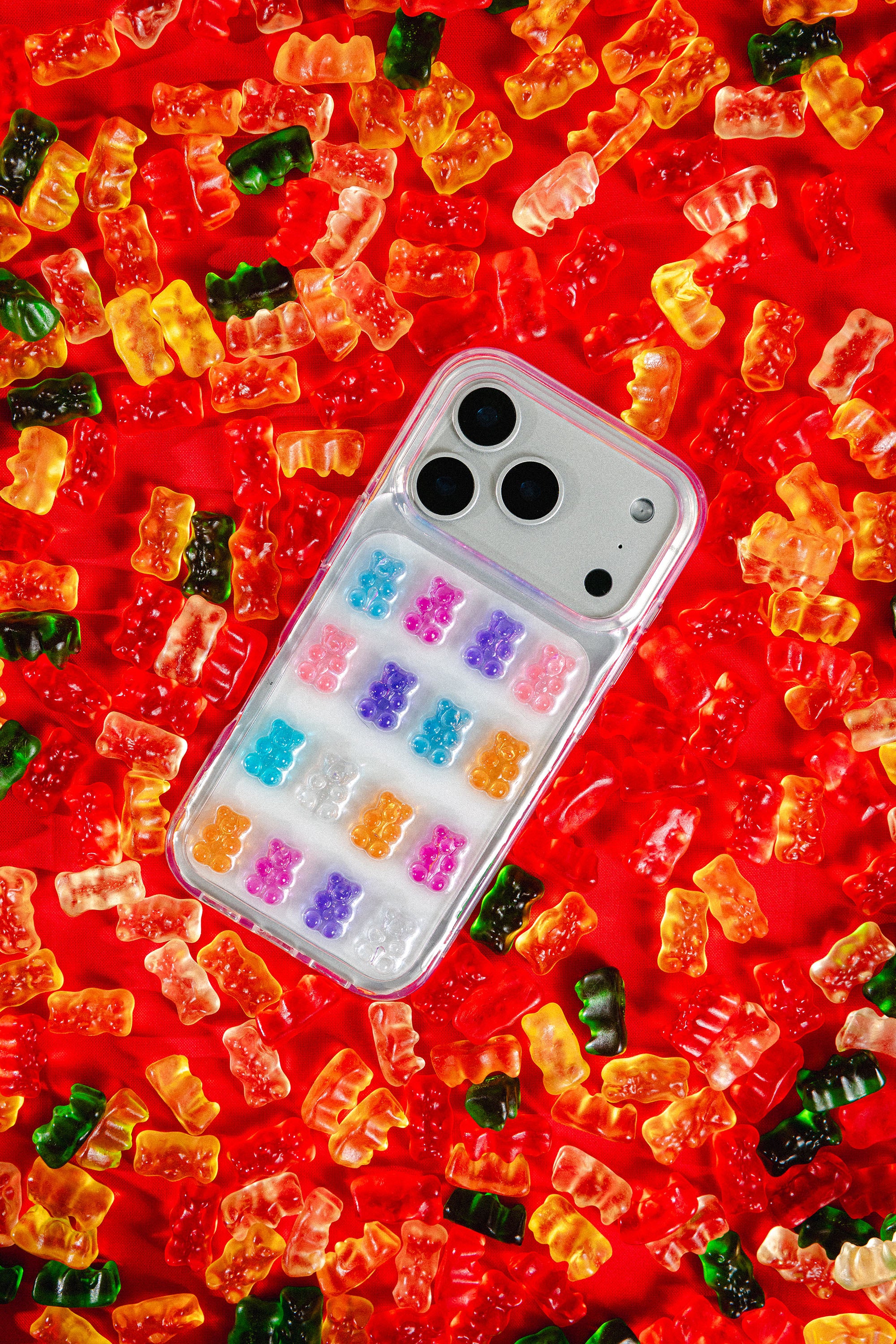 Phone case with colorful grid of gummy bears design on a bed of gummy bears